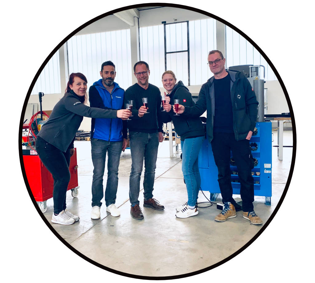 Das Team der MONTARA GmbH in der Hydraulikwerkstatt vor einer Hydraulikpresse und einem mobilen Rohrbiegegerät