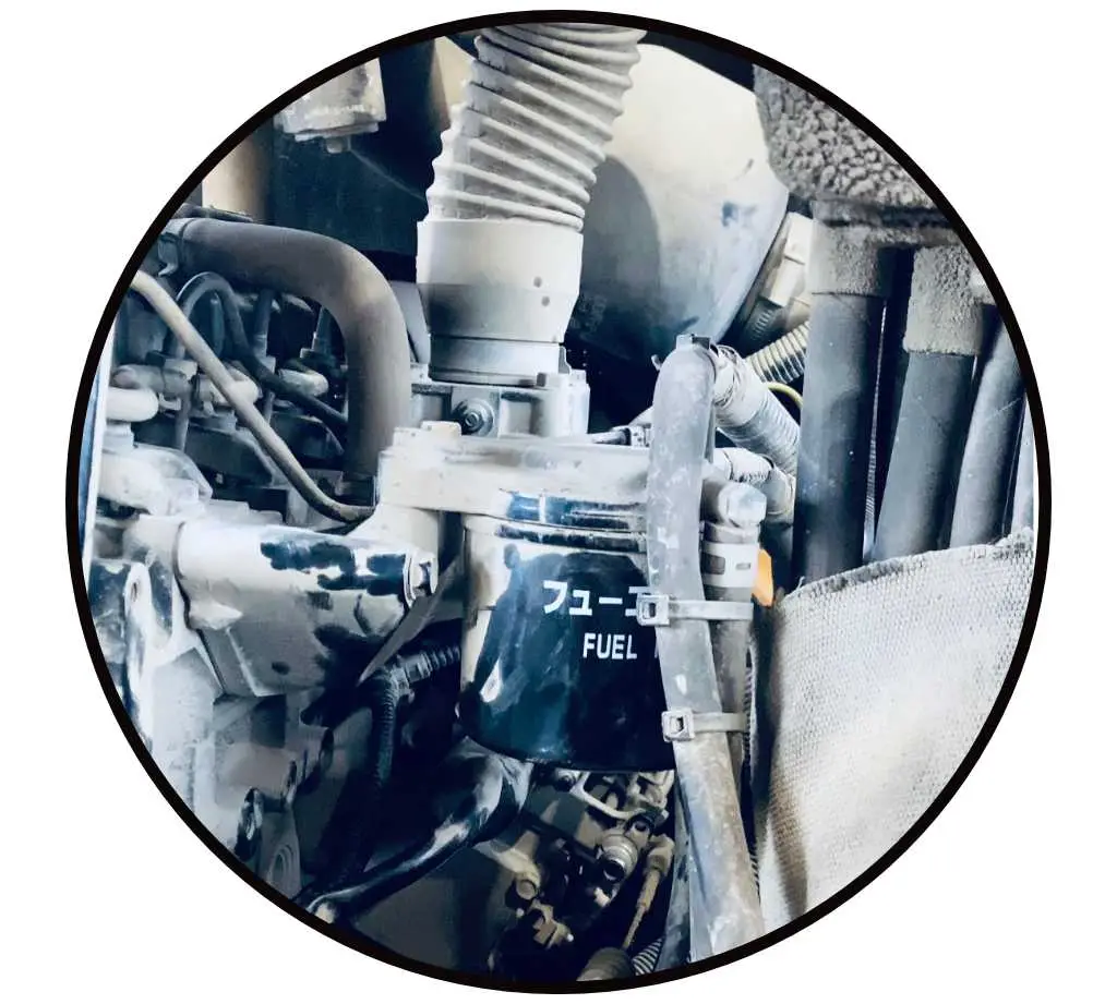 Hydraulik Fehlersuche im inneren einer Baumaschine. Das Bild zeigt Hydraulikschläuche und einen Kraftstofffilter
